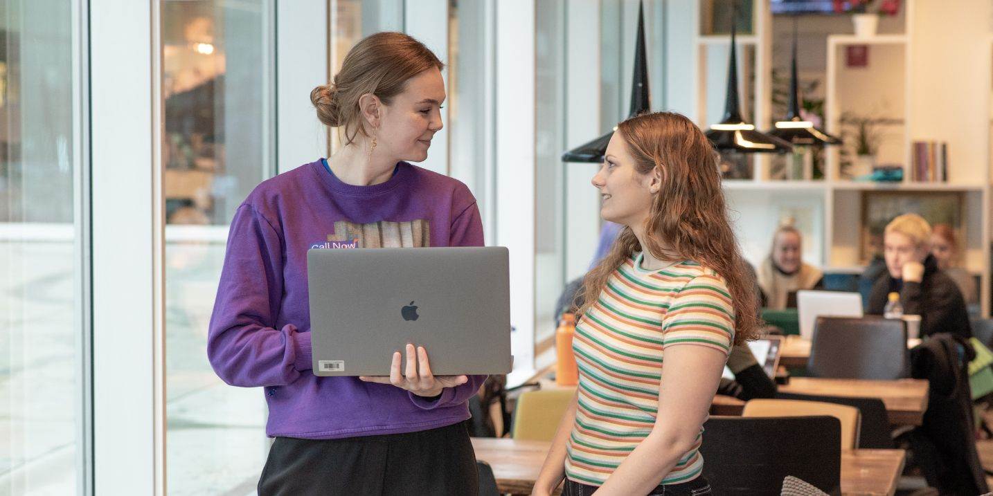 To kvindelige studerende, der taler sammen om det, de ser på en computerskærm